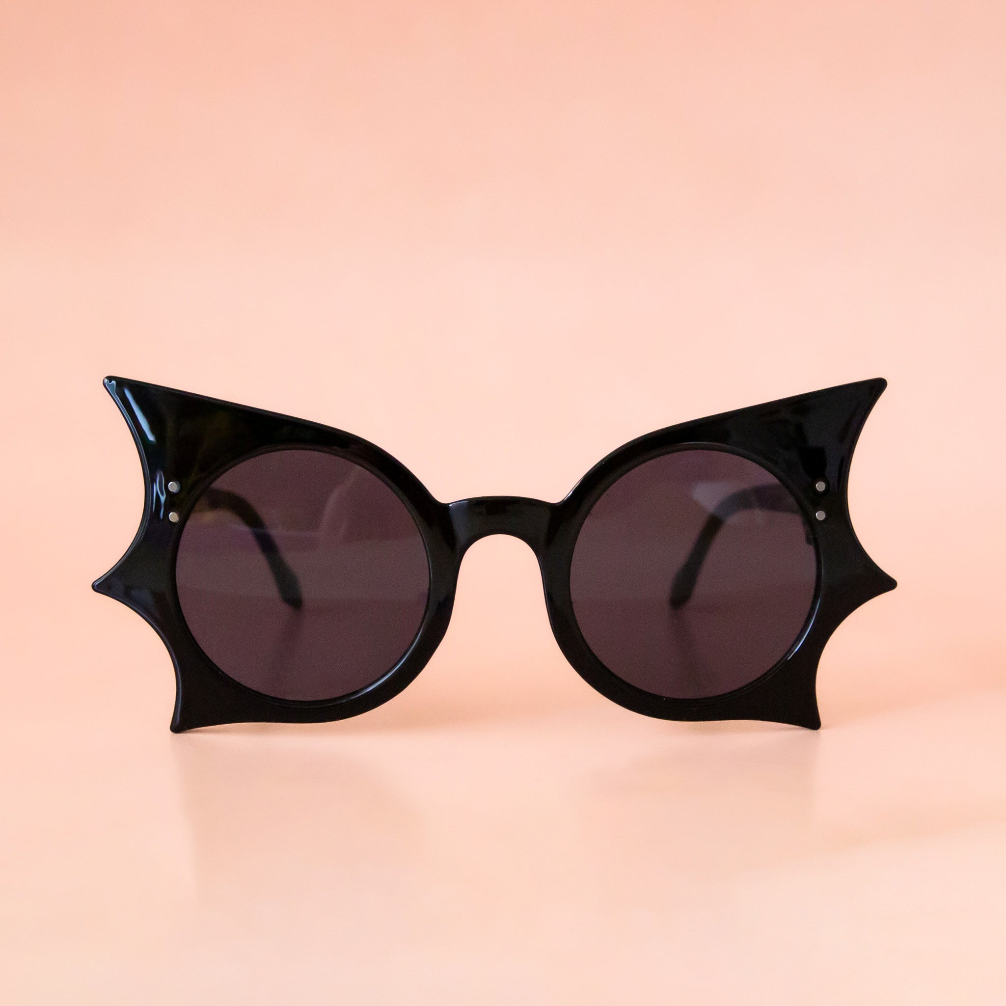 Black sunglasses with bat wing details around the edges of the frames. 